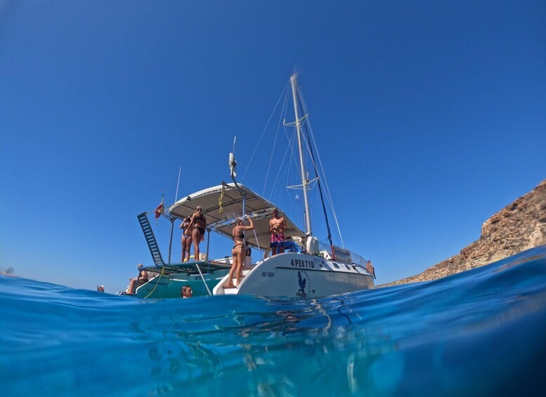 A sailboat with people on board, sailing on clear blue water. 2