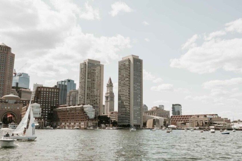A city skyline with tall buildings, a body of water, and a sailboat. 2
