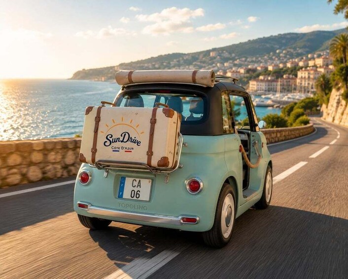 A vintage car with a luggage rack and a license plate CA 06, driving on a coastal road with a view of the sea and buildings in the background. 3