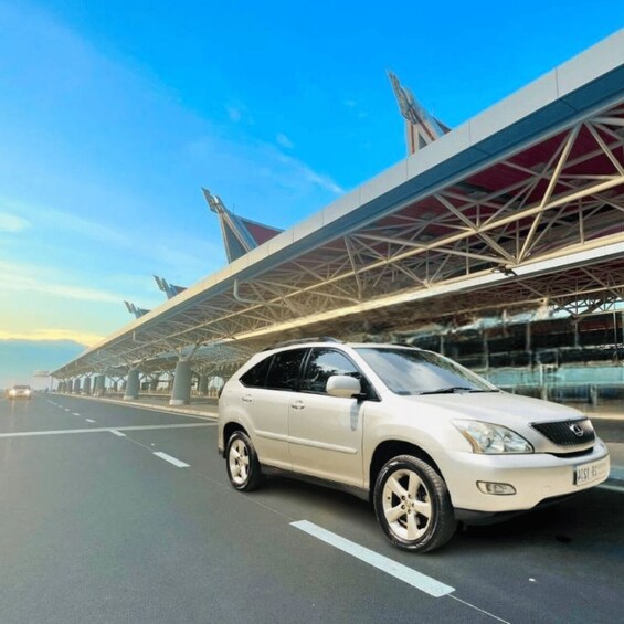 A white SUV on a multi-lane highway with a modern bridge overhead. 1