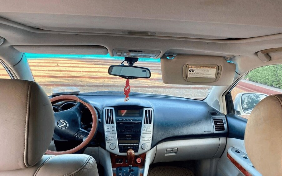 The interior of a car with leather seats, a steering wheel, a dashboard with a radio, and a rearview mirror. 4