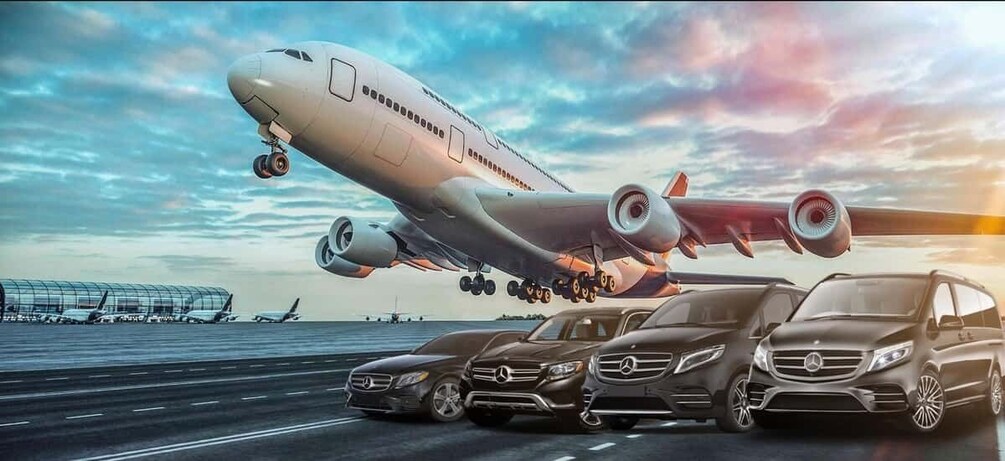 A large airplane landing on a runway with four luxury cars parked beside it. 1