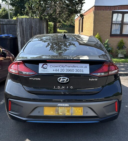 A black Hyundai IONIQ hybrid car with a CrownCity Transfers.co.uk sign on the rear window. 3