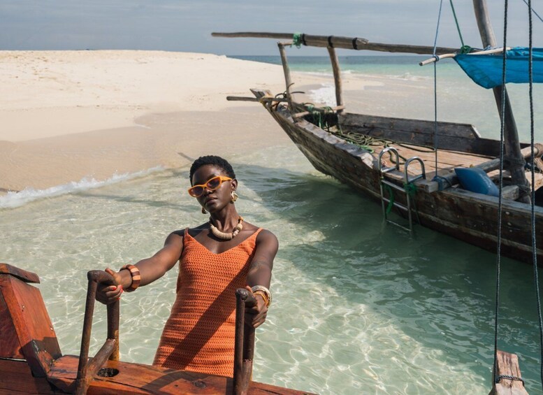 A person on a wooden boat near a sandy beach with clear water. 1