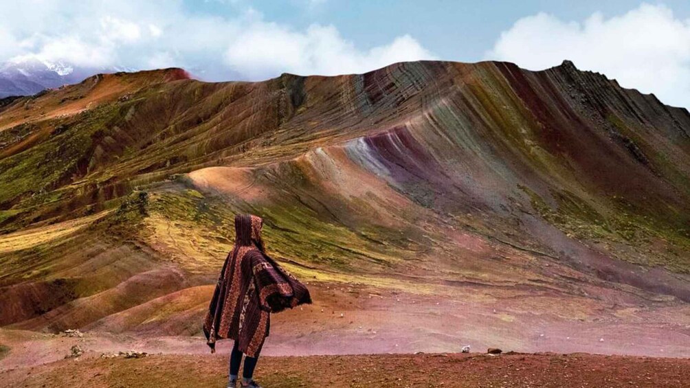 A person standing in a colorful, rocky landscape with layered hills. 1
