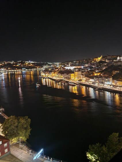 A nighttime cityscape with illuminated buildings and a river reflecting lights. 1