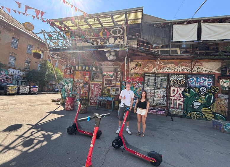 Un edificio con graffiti e due scooter elettrici rossi parcheggiati davanti. 3