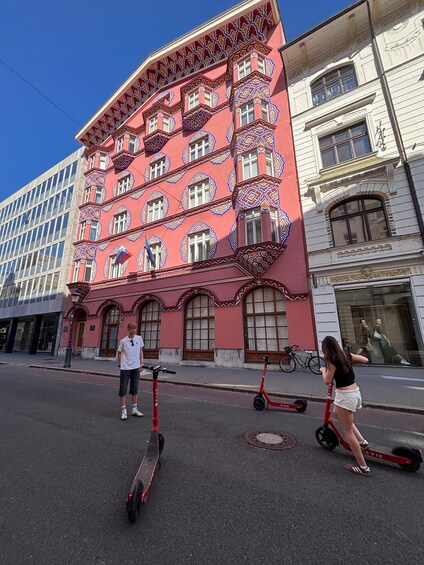 Una strada con un edificio rosso caratterizzato da decorazioni elaborate e numerose finestre. 4