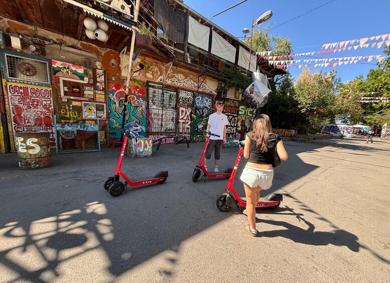 Una strada con edifici imbrattati da graffiti, uno scooter rosso e una persona che cammina. 5
