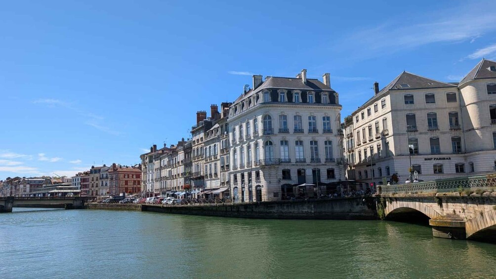 A riverside view with historic buildings, a bridge, and a calm water body. 3