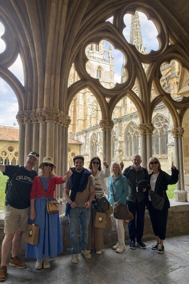 A group of people standing under a Gothic-style archway with a historic building in the background. 1