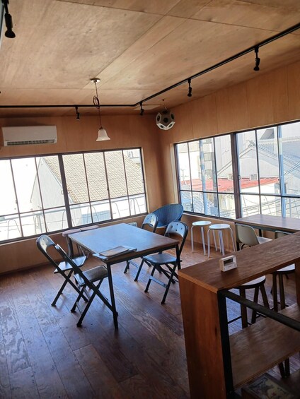 A room with wooden floors, tables, chairs, and large windows. 2