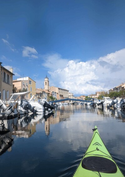 A calm canal with boats docked, buildings lining the water, and a clear sky. 2