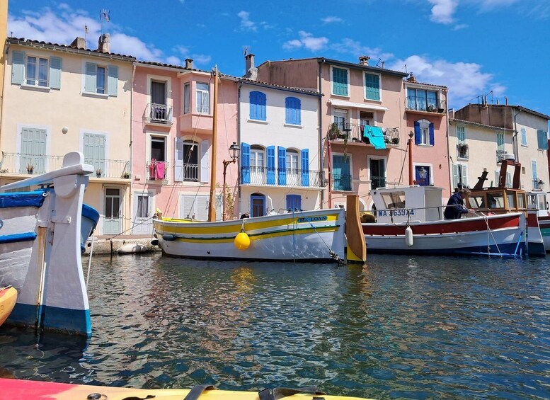 A row of colorful buildings with blue shutters and a calm waterway with boats. 4