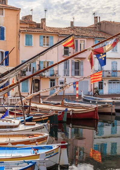 A marina with boats docked, buildings with blue shutters, and flags. 1