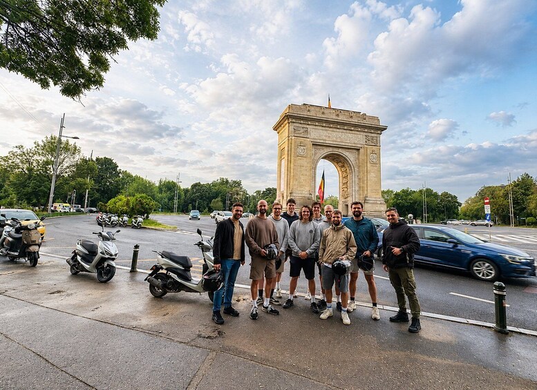 A group of people standing in front of the Arc de Triomphe in Paris. 1