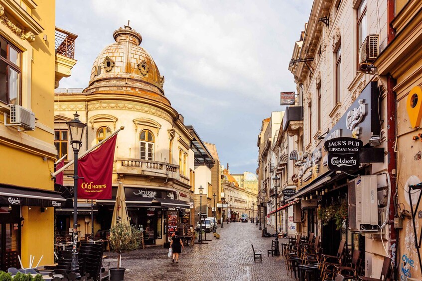 A cobblestone street lined with historic buildings, a prominent dome structure, and outdoor seating areas of cafes. 5