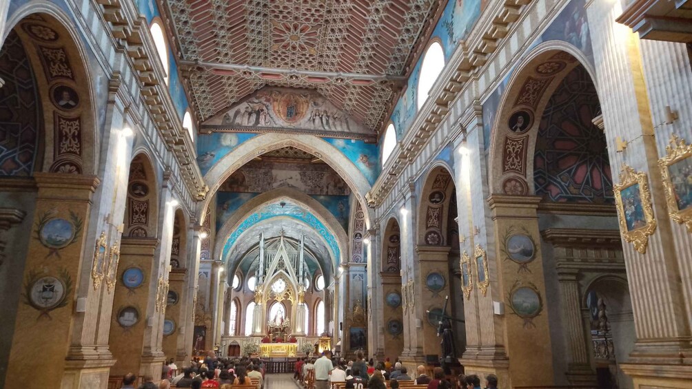 An ornate church interior with high vaulted ceilings, arched windows, and religious paintings. 4