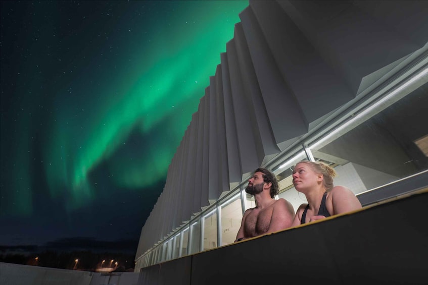 A person looking at the Northern Lights from a building with a modern design. 1