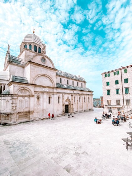 A historic building with a dome and arches, surrounded by a plaza with people and outdoor seating. 3