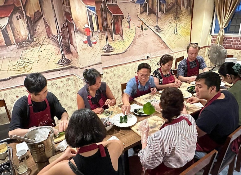 A group of people dining at a restaurant with a mural depicting a street scene. 1