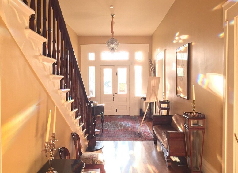 A grand staircase with a chandelier, a wooden bench, and a framed picture on the wall. 3