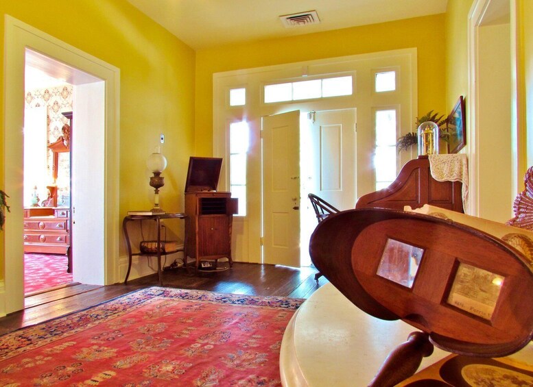 A room with yellow walls, a red carpet, a wooden piano, and a door leading to another room. 4