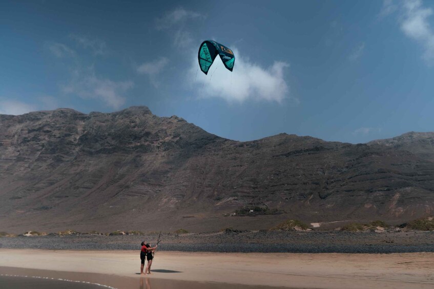 A person flying a kite on a beach with mountains in the background. 4