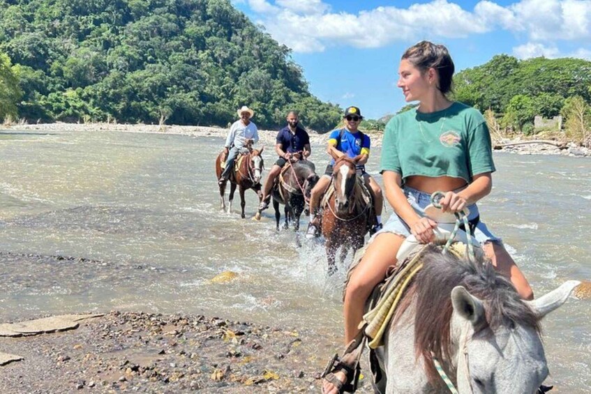 A group of people riding horses along a riverbank. 3