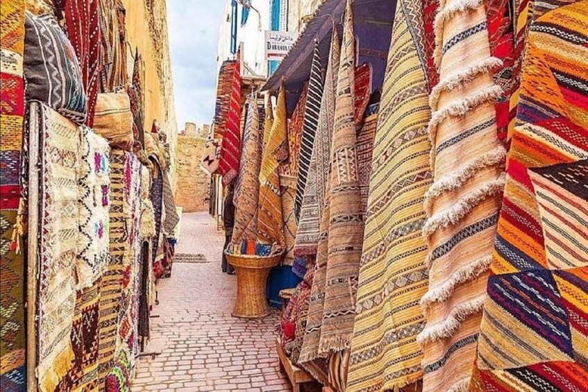 A narrow street lined with colorful textiles and rugs. 2