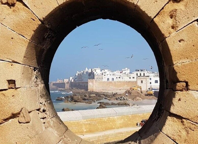 A coastal cityscape viewed through a circular stone archway. 5