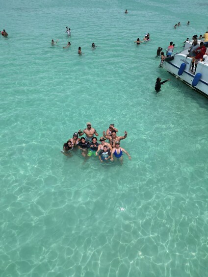 A group of people floating on a raft in clear turquoise water, with a boat docked nearby. 4