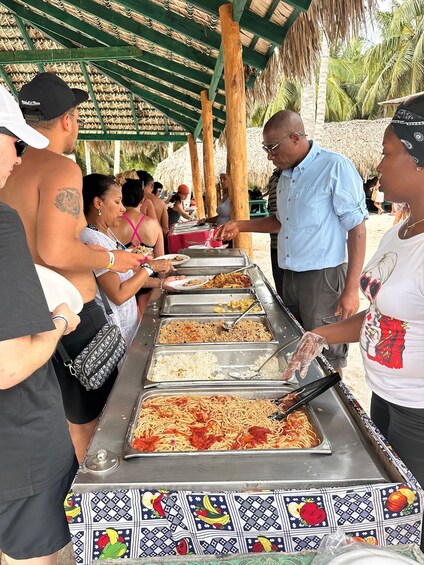 A buffet line with various food options under a thatched roof. 5