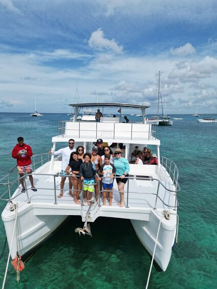 A group of people on a white boat with a clear blue sea and other boats in the background. 3
