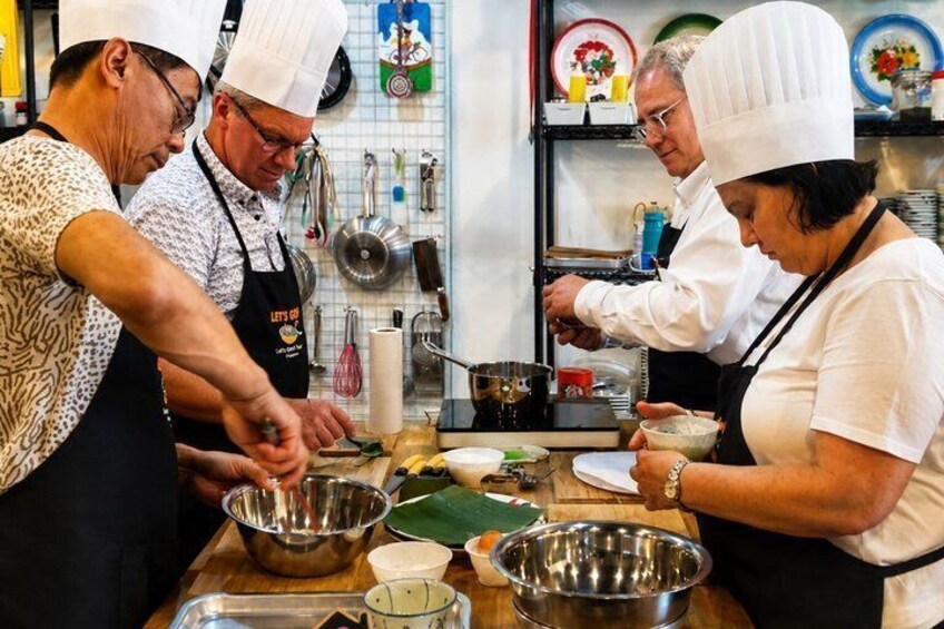 Chefs in white hats and aprons preparing food in a kitchen with stainless steel bowls and cooking utensils. 4