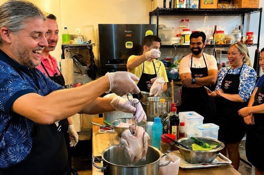 A group of people in a kitchen preparing food, with a pot on the counter and various kitchen items around. 1