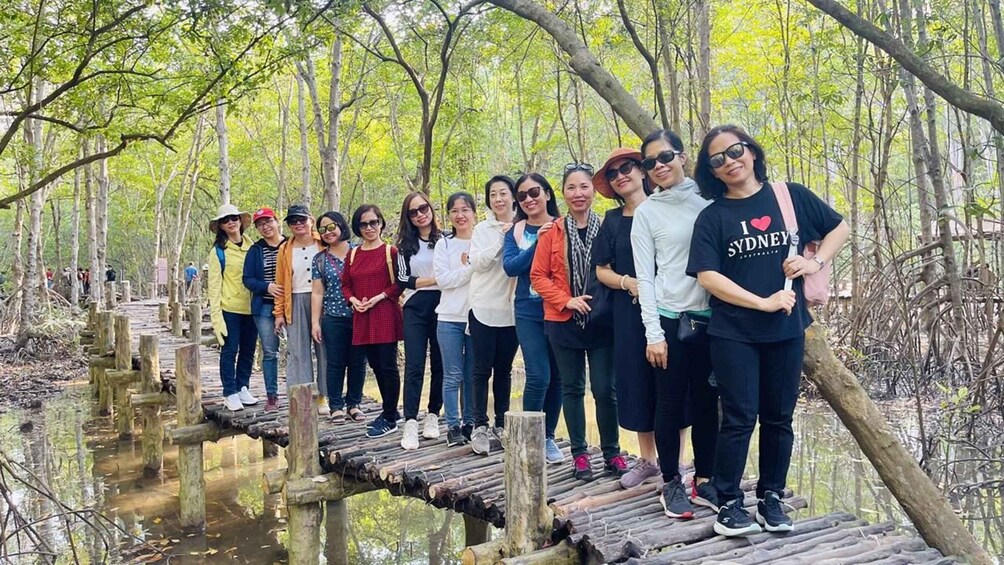 A group of people standing on a wooden bridge in a forested area. 4