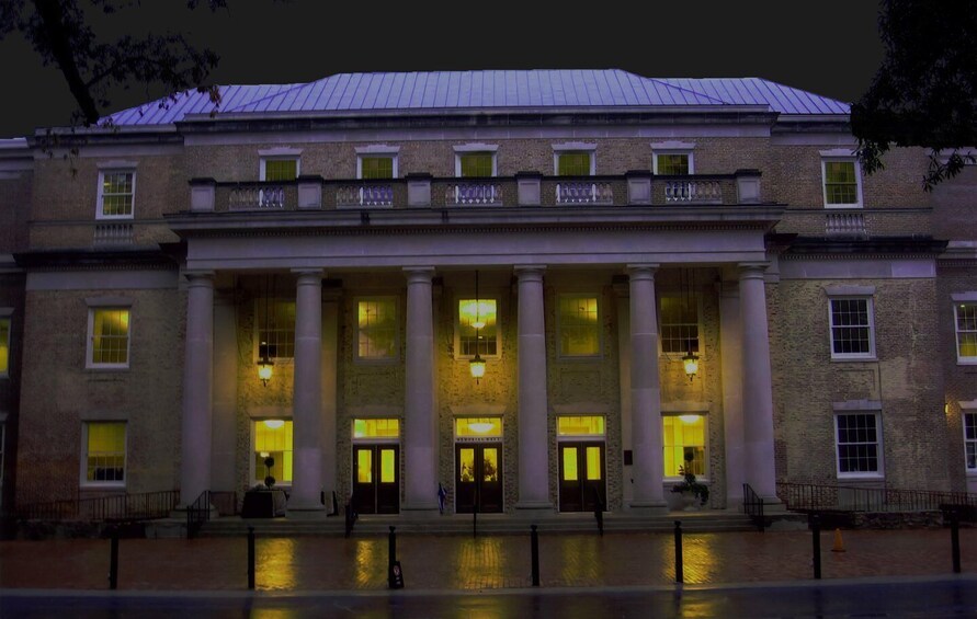 A large, historic building with a symmetrical facade, large columns, and illuminated windows at night. 2