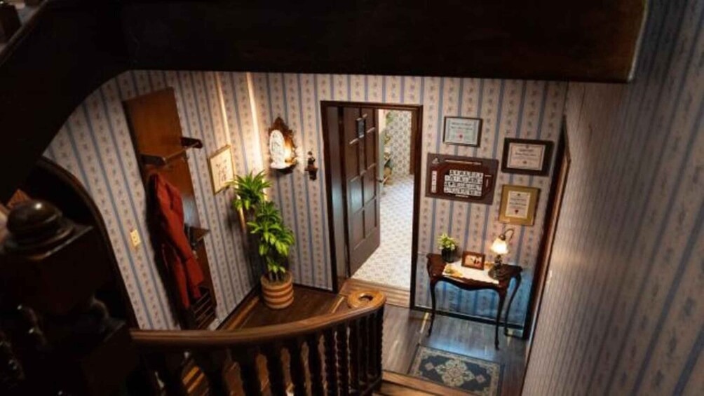 A staircase with a wooden handrail, a potted plant, and a small table with a lamp. 3