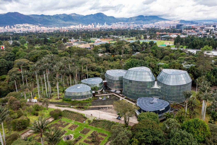 A botanical garden with large greenhouses and a cityscape in the background. 1