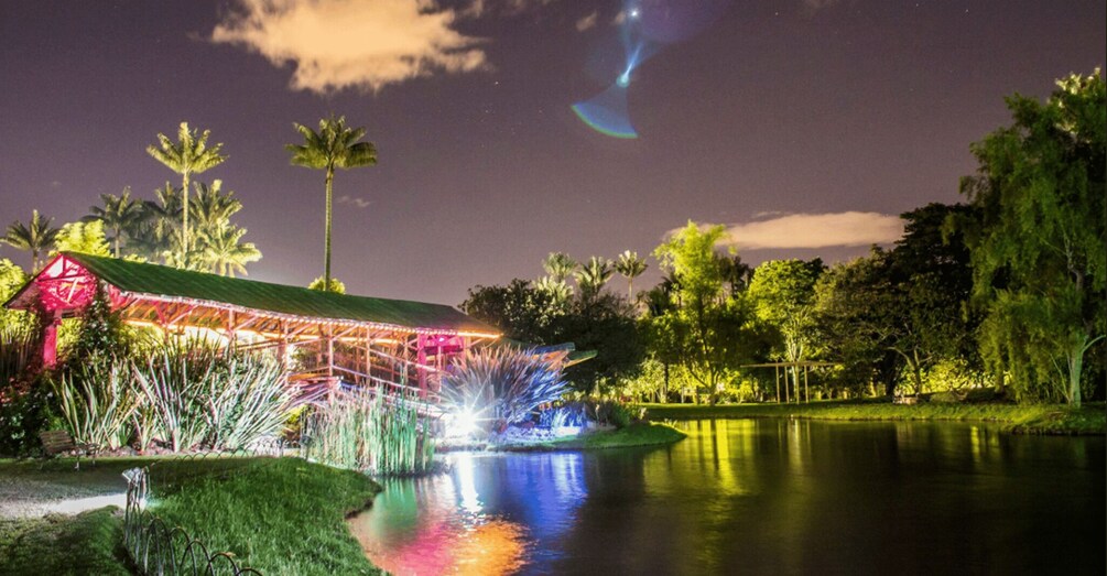 A brightly lit gazebo with a water feature in a park at night. 2