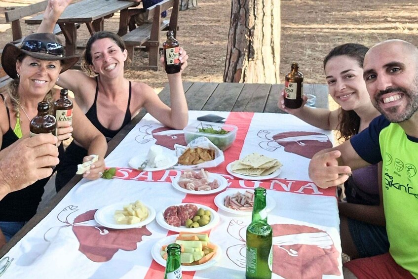 A group of people at an outdoor picnic with a table set with food and drinks. 5