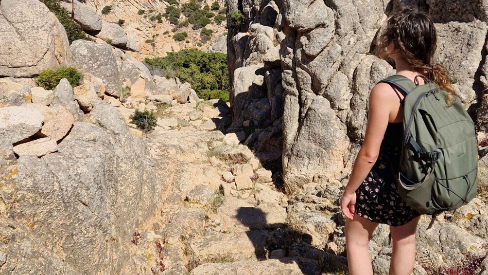 A person hiking on rocky terrain with a backpack. 3