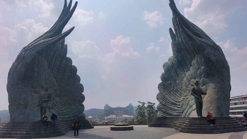 A large sculpture with two large wings and a figure standing on top. 1