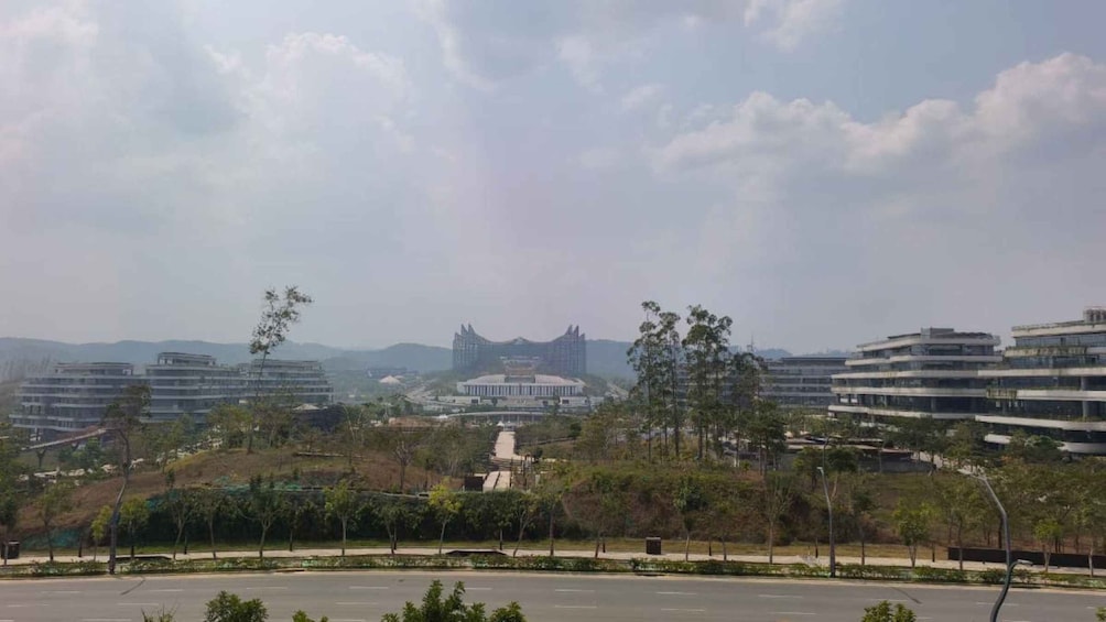 A cityscape with modern buildings, a large central structure, and surrounding greenery. 3