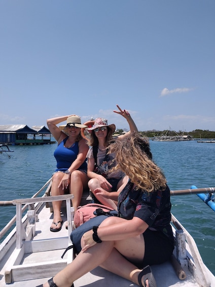 Three people sitting on a boat with water and overwater structures in the background. 2
