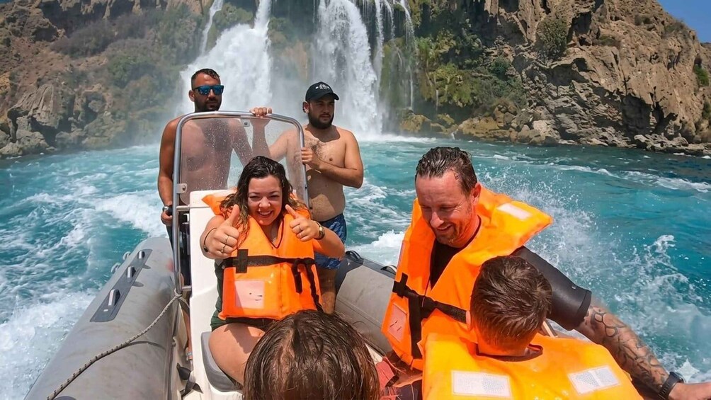 A group of people on a boat with a waterfall in the background. 5