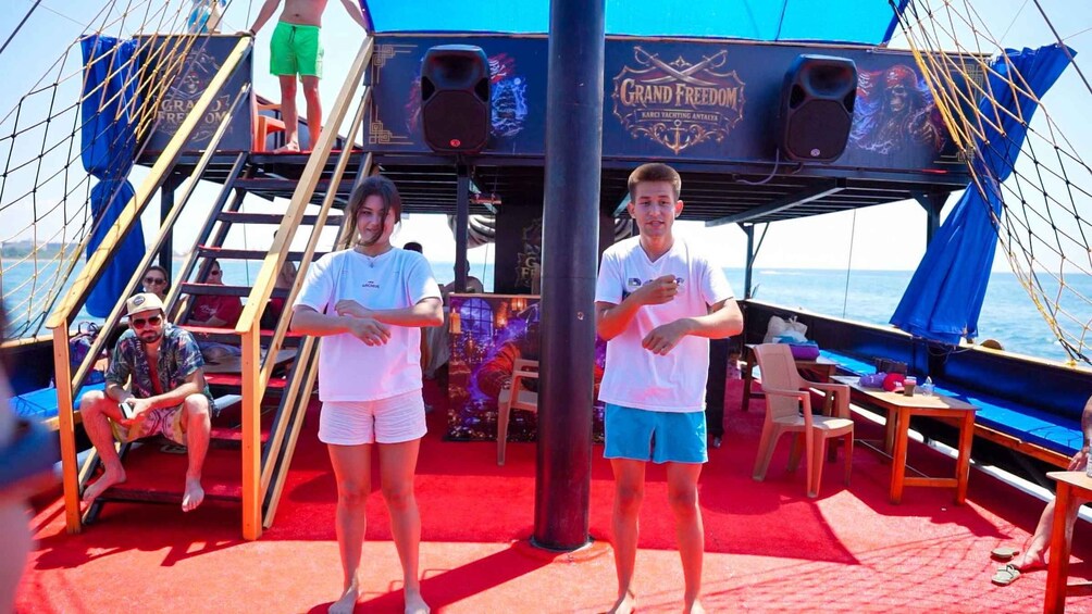 A yacht deck with a red carpet, people dancing, and a sign reading 'Grand Freedom.' 4