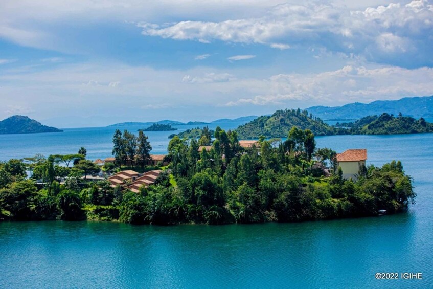 A lush island with dense greenery and traditional buildings, surrounded by calm blue waters and distant mountains. 2