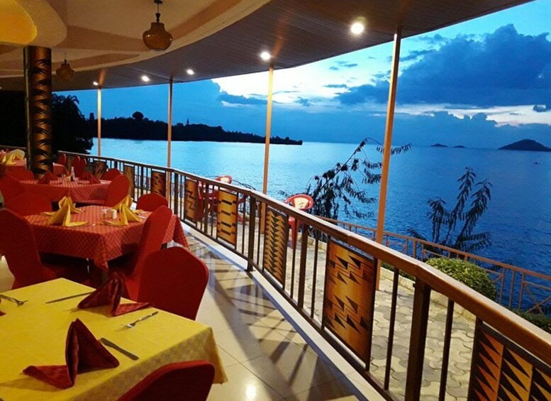 An outdoor dining area with tables set for two, overlooking a body of water with islands in the distance. 1